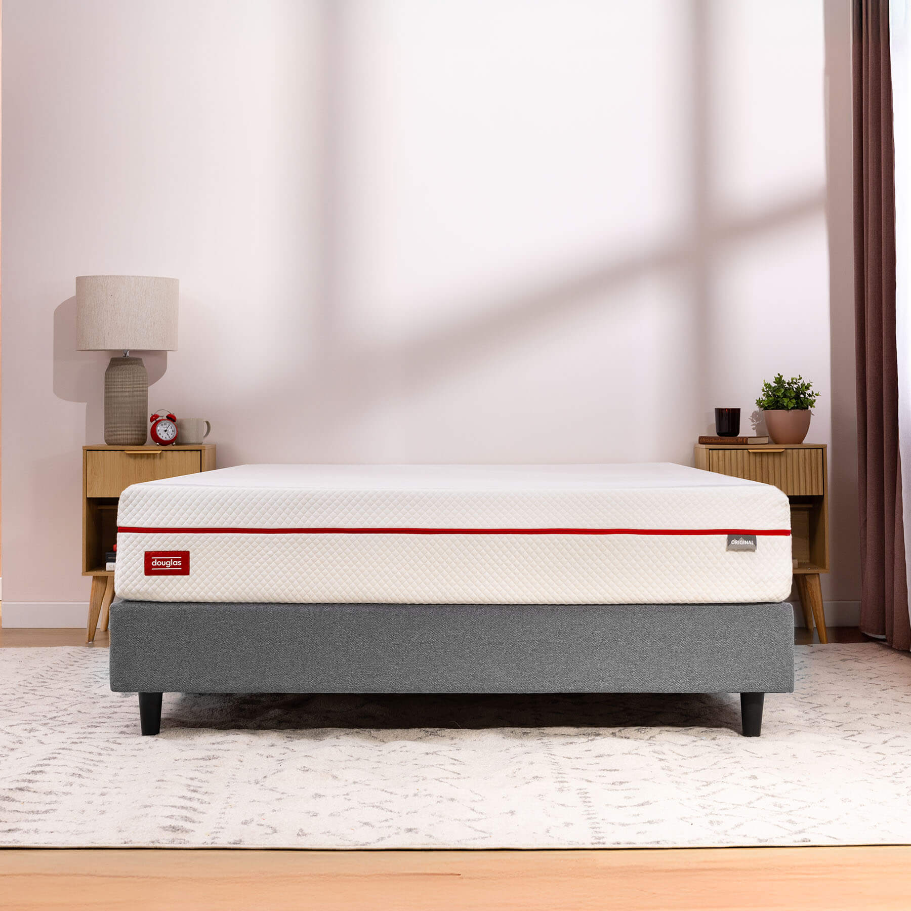 A Douglas mattress featured on a grey platform bed frame in a simple bedroom