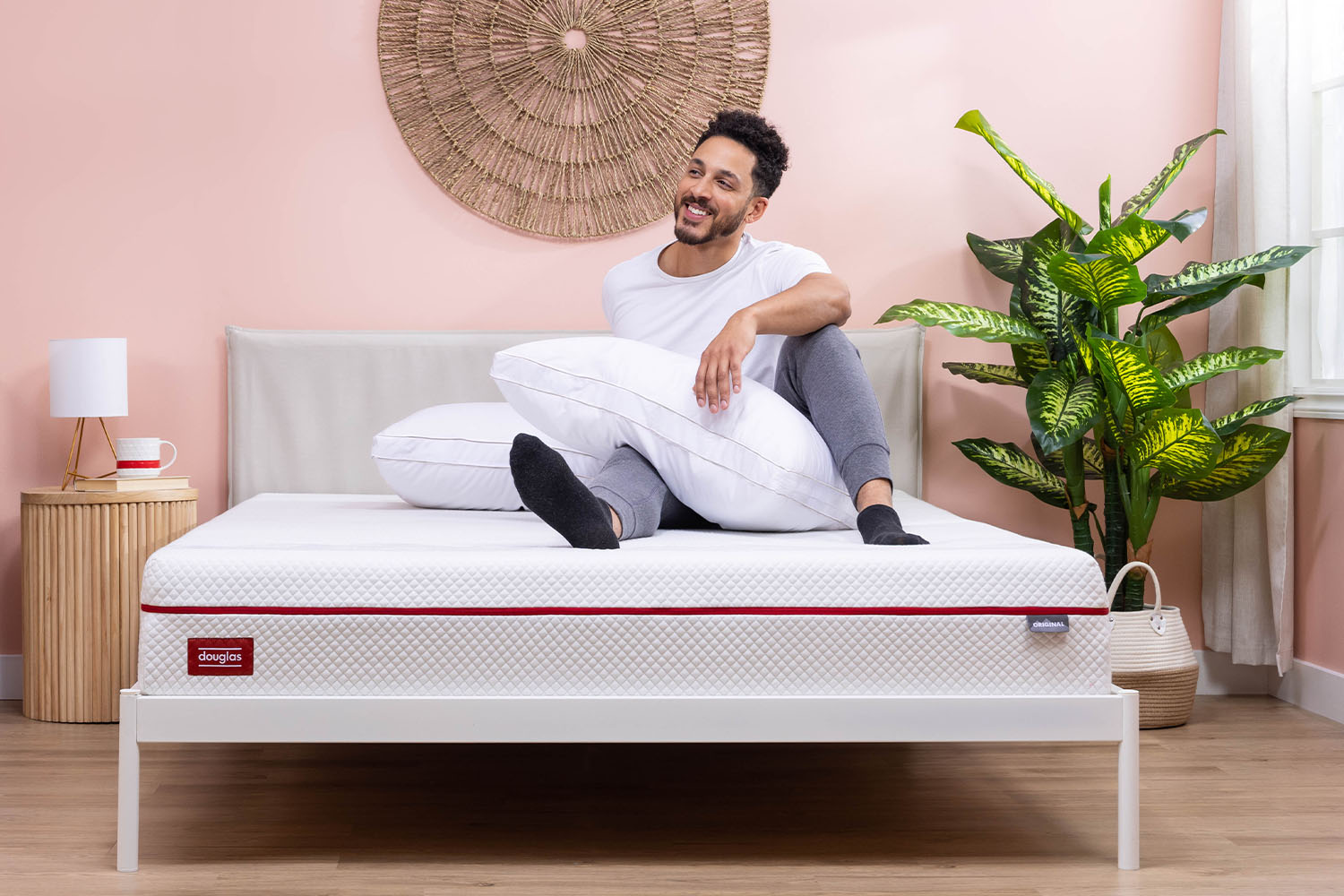 A man resting on a Douglas mattress, holding two Adjustable Memory Foam Pillows