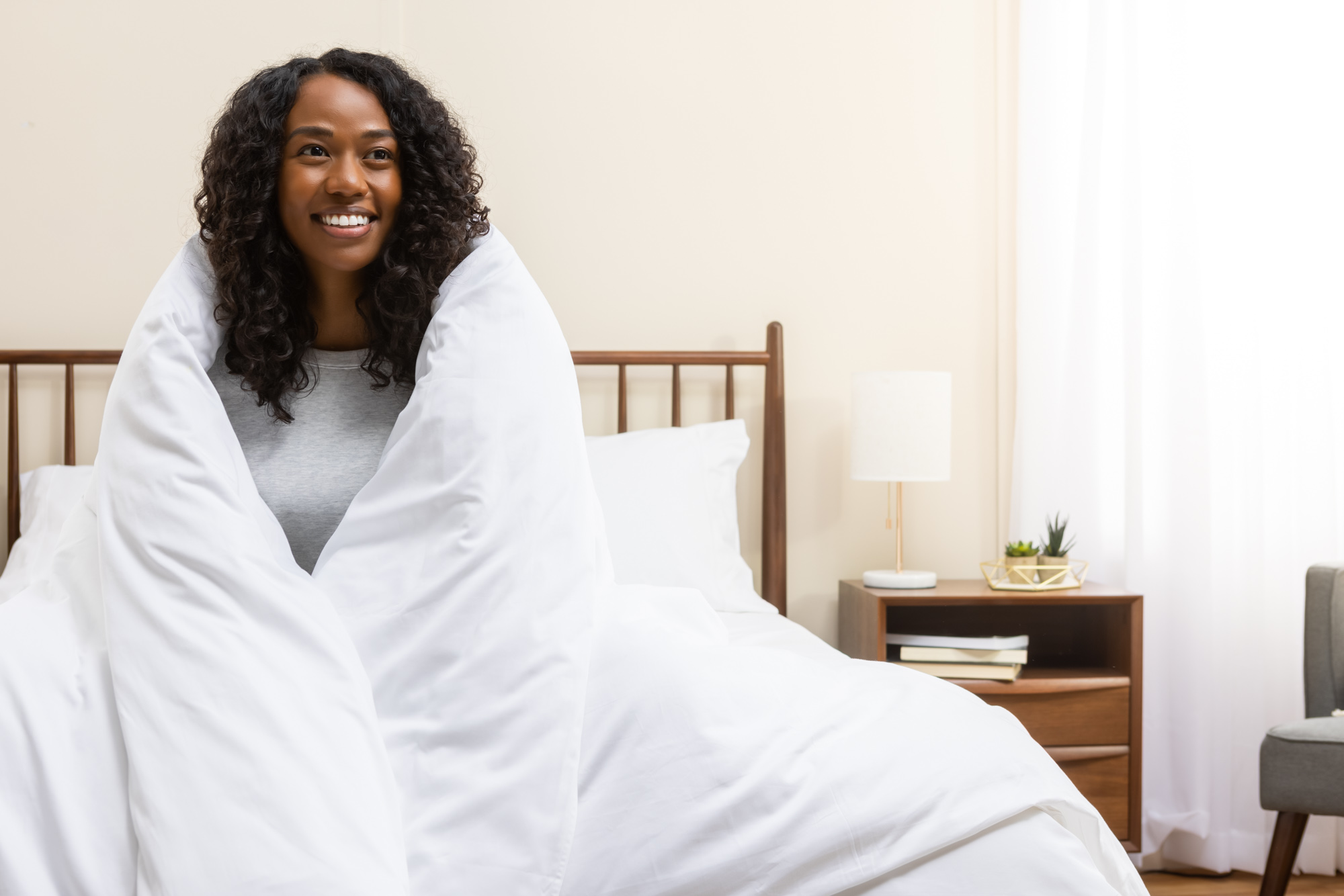 Woman smiling with her sateen cotton duvet and cover wrapped around her body 