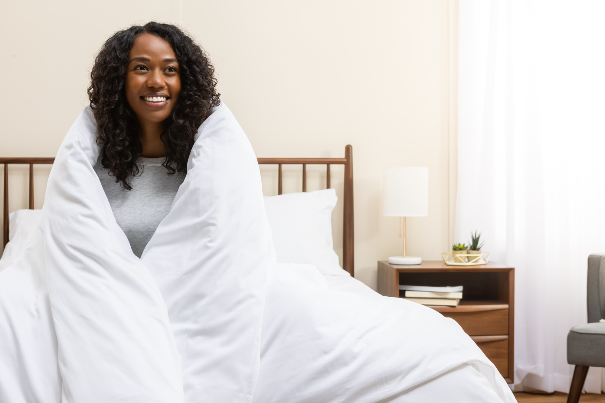 GM-DC-001-20210929-LR-9 Woman smiling with her sateen cotton duvet and cover wrapped around her body