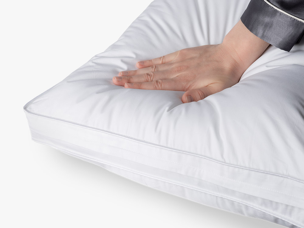 Hand pressing into the plush surface of the Microfiber Pillow