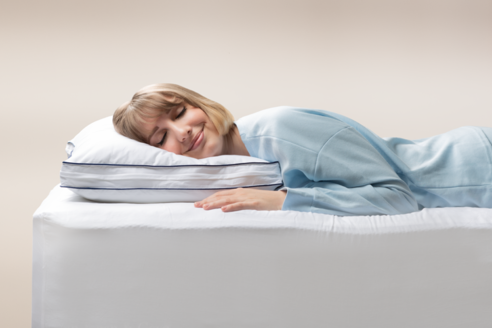 Woman in light blue pajamas peacefully sleeping on her side, head resting on the Adjustable Memory Foam Pillow
