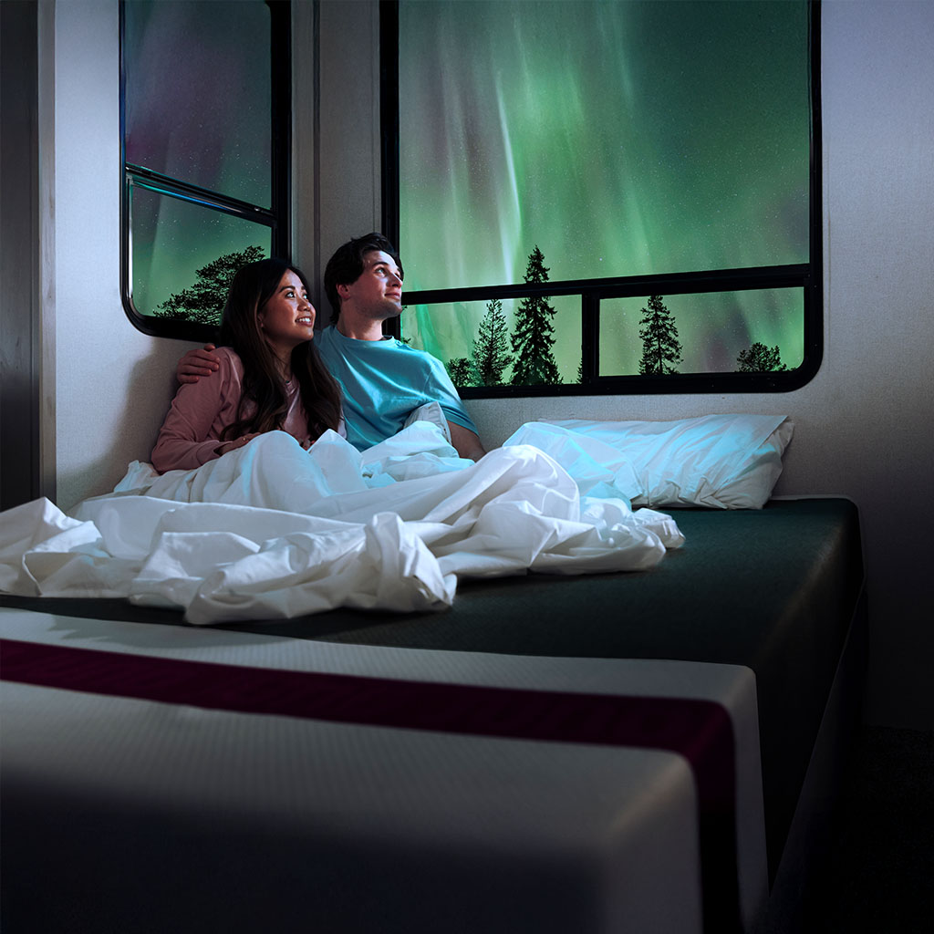 Couple sitting on the Juno Hybrid RV Mattress looking at Northern Lights