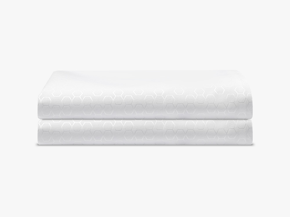 Pillow Protector Folded Two Pillow protectors with light circular patterns sit atop one another, neatly folded.