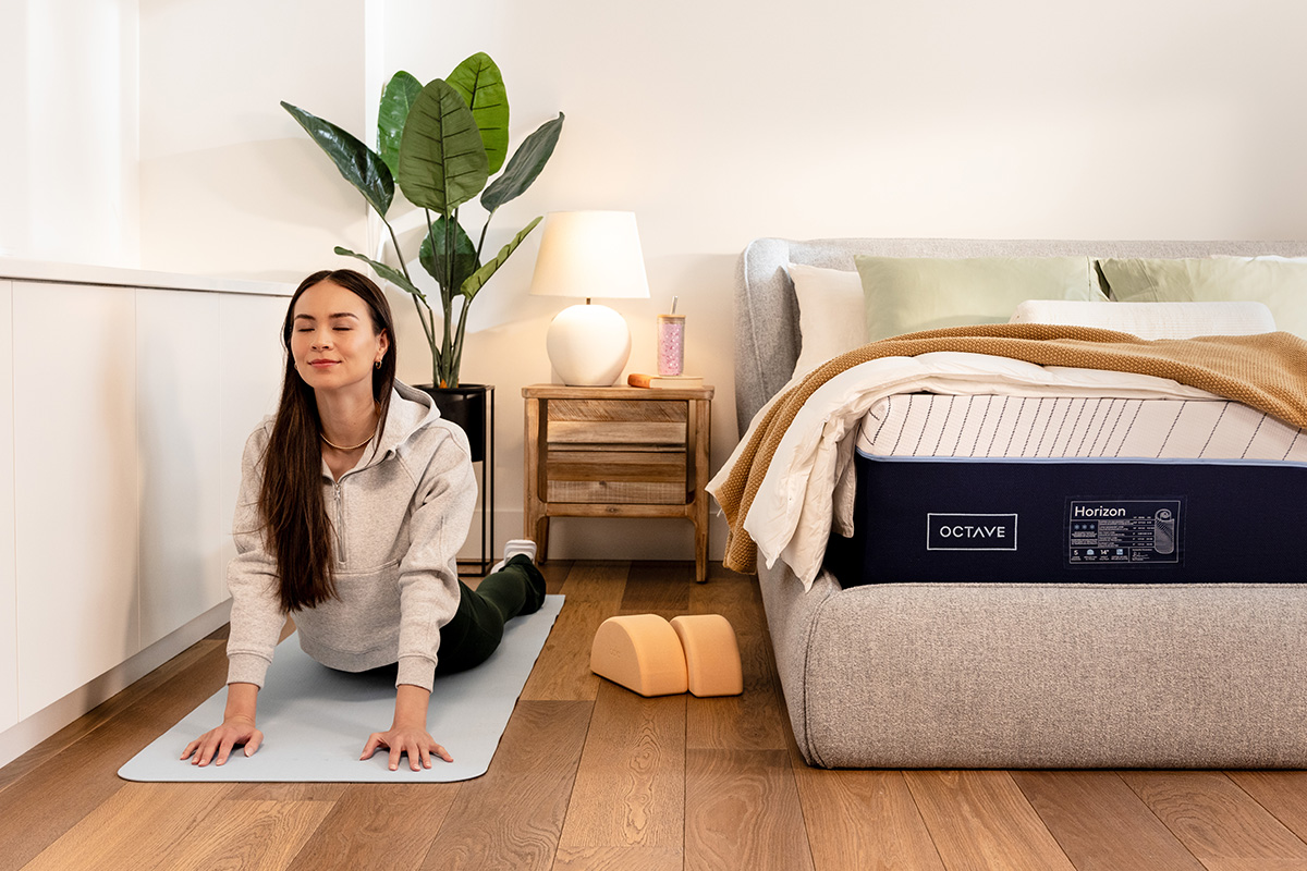 Une femme assise sur un matelas Octave, &eacute;tirant ses bras grand ouverts.