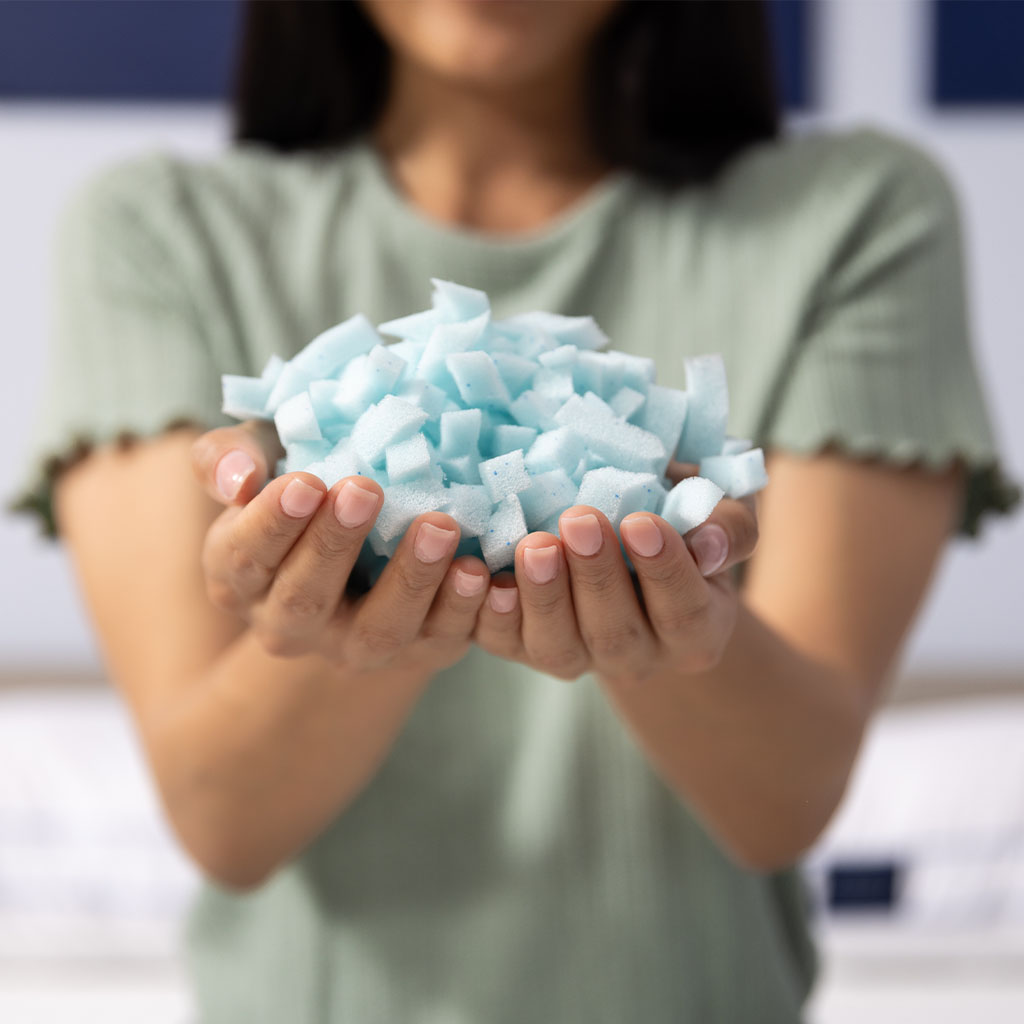 A closeup shot of hands holding a pile of memory foam filling.