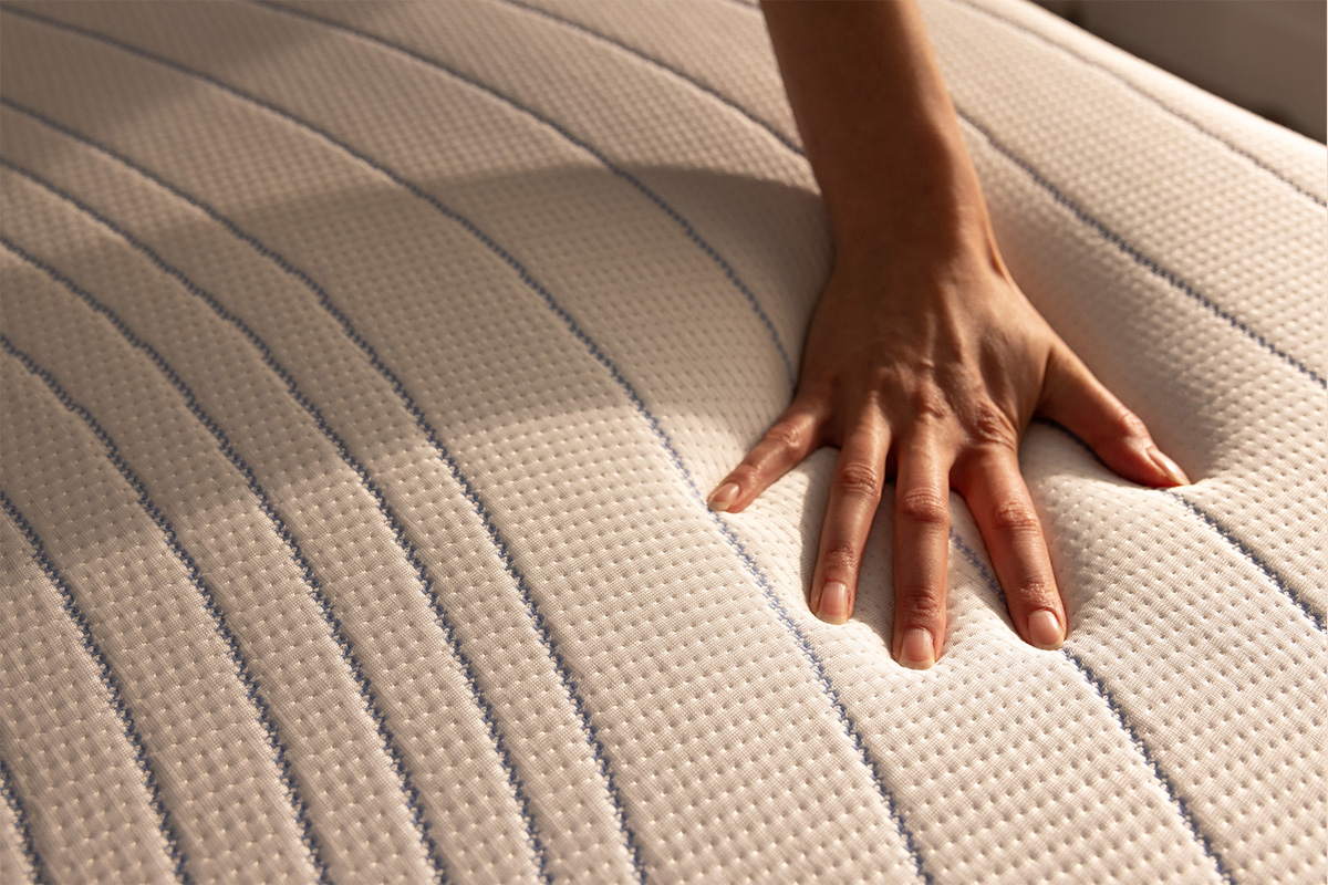Vue rapproch&eacute;e de la housse du matelas Octave Vista, avec une main tirant la fermeture &eacute;clair.