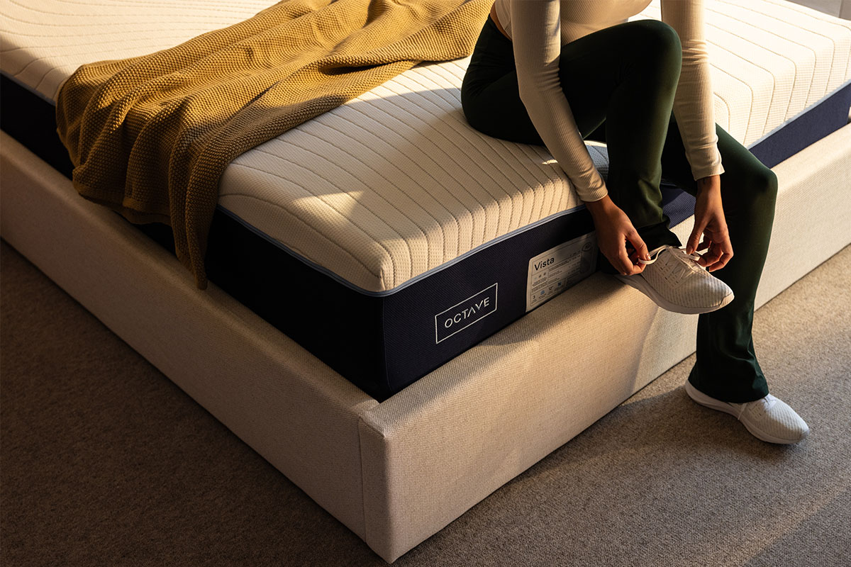 Femme assise sur le bord du lit sur un matelas Octave Vista.