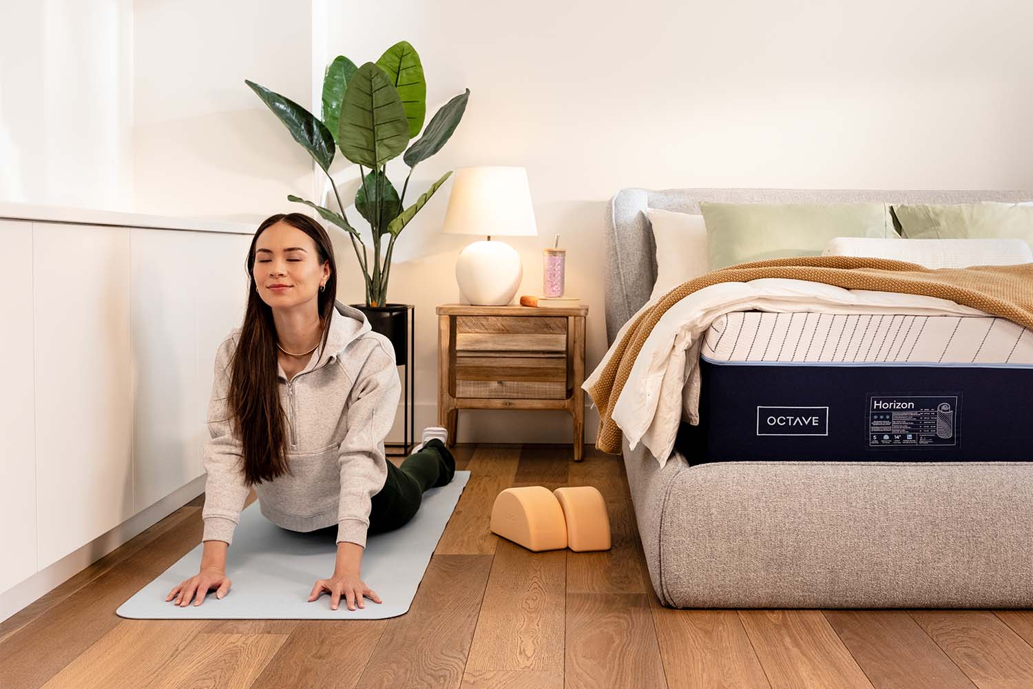 A woman stretching her back next to an Octave Horizon mattress.