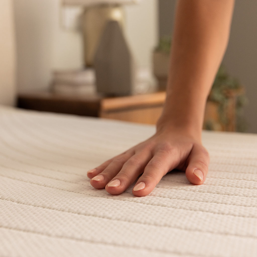 Closeup of a hand touching the plush texture of the mattress top