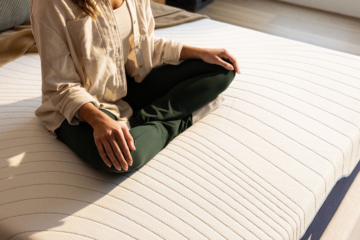 Woman sitting cross-legged on an Octave Vista mattress.