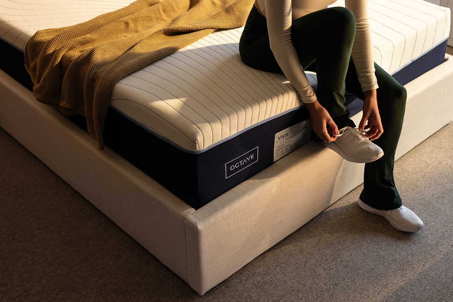 Woman sitting on the side of the bed on an Octave Vista mattress.