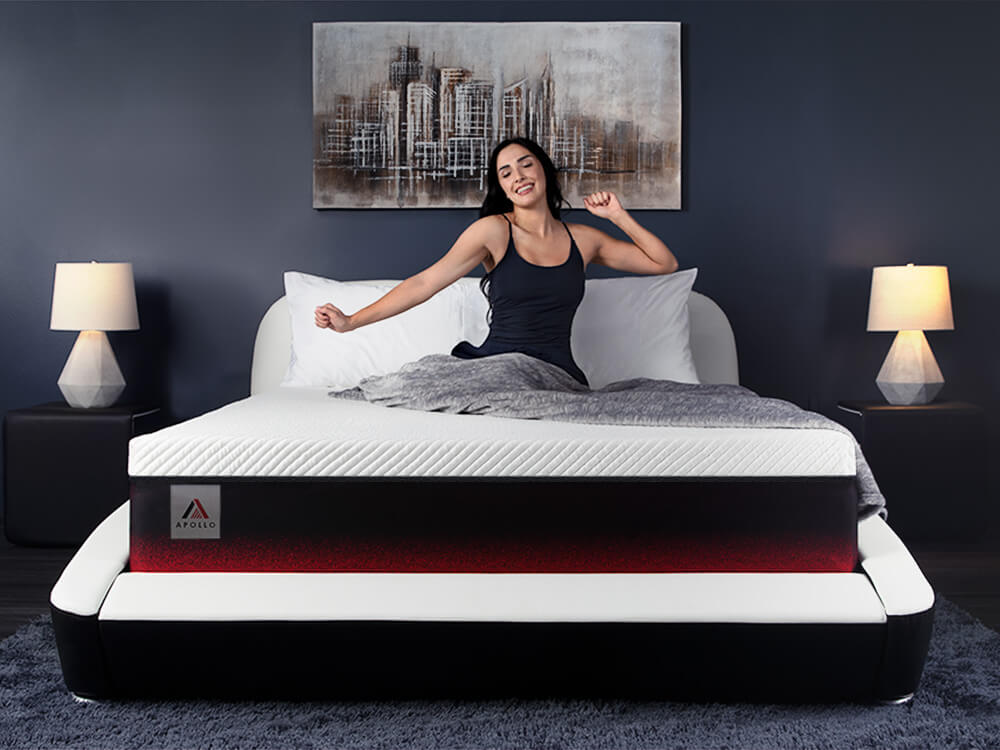 Woman sitting on the Apollo mattress and stretching out her arms