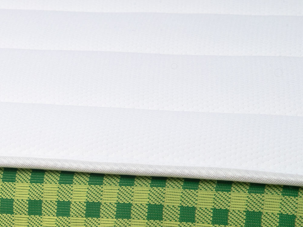 Close-up of the white cover and green plaid ribbon along the Brunswick classic spring mattress