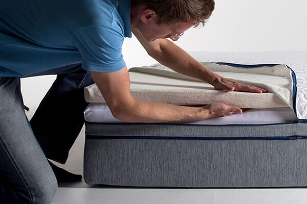 Image of GoodMorning.com founder, Sam Prochazka, carefully inspecting the Comfort+ layer on a Novosbed mattress.