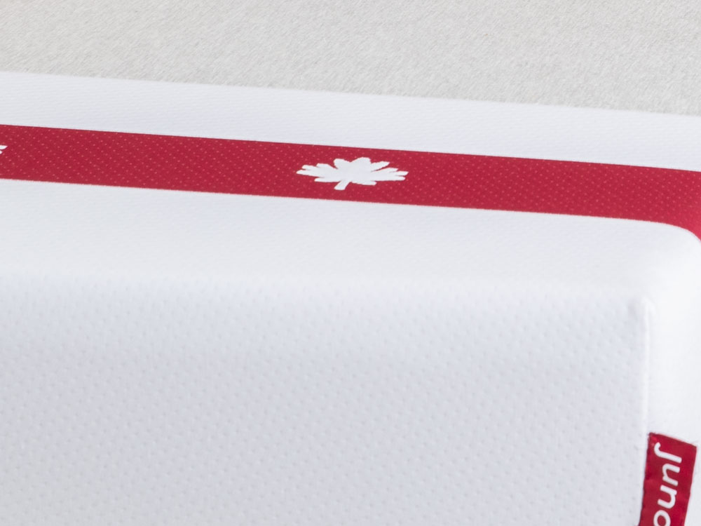 juno-2 Closeup detail of the Juno mattress cover, including the red stripe and maple leaf design.