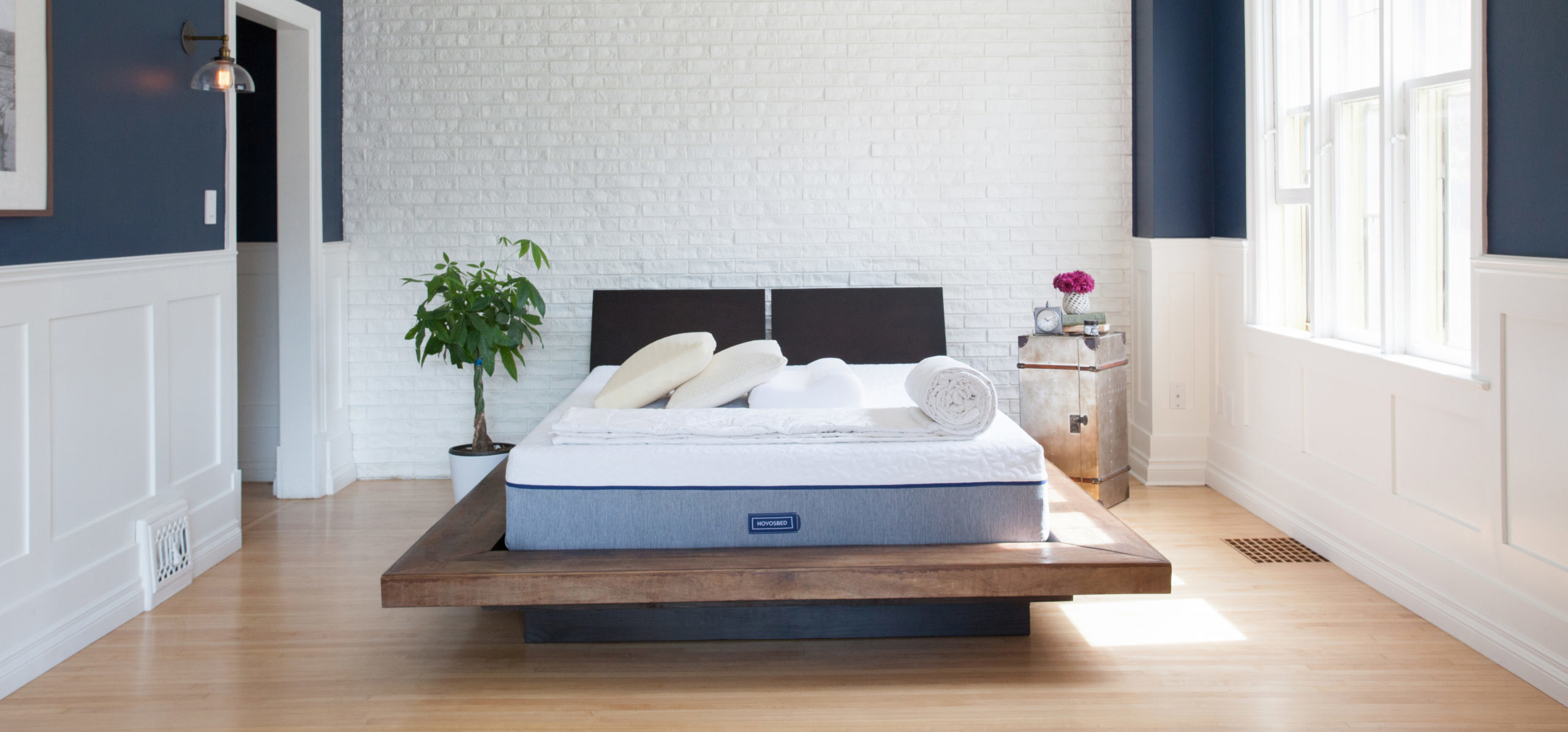 A Novosbed by Goodmorning.com sits on a raised wood platform in a bright, white room.