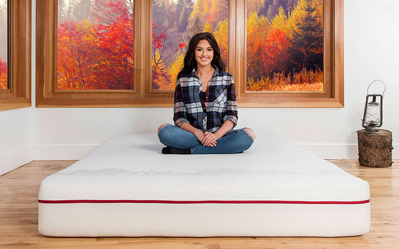 Woman sitting on a Douglas mattress with a Canadian sunrise in the background